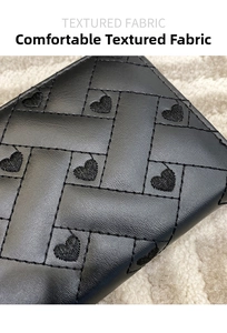 Macro shot of black leather wallet with quilted cross-stitching and heart embroidery details