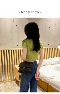 Modèle portant un sac bandoulière en cuir matelassé noir avec chaîne et boucle dorées
