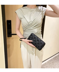 Close-up of black long wallet with heart quilted pattern held by a model with wrist strap