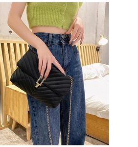 Modern black quilted chain bag with V-shaped stitching shown on casual model outfit