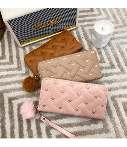 Macro detail of woven texture long wallets with heart embroidery and fluffy charms