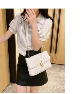Close-up of a white quilted crossbody bag with gold chain and V-shaped stitching detail