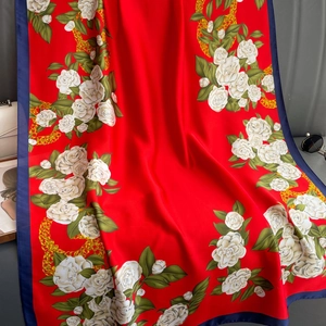Detail of red floral satin shawl featuring white rose prints and golden chain patterns