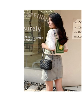Detail of black quilted shoulder bag featuring golden logo plate and wide BAG.19 strap