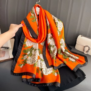 Detailed texture of satin silk shawl with orange floral camellia print and black borders