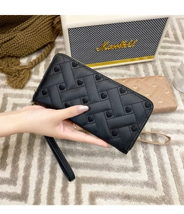 Close-up of heart embroidered long wallets with hand straps on a textured surface