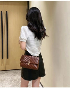 Deep brown quilted leather chain bag with gold buckle clasp worn by a model