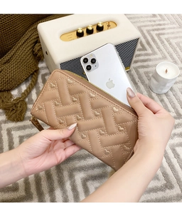 Detail of a quilted leather long wallet in nude with gold heart embroidery and zip closure