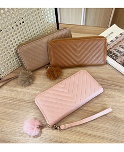 Detailed view of quilted zip-around wallets with fur pom-pom charms and wrist straps