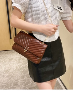 Close-up of brown quilted leather crossbody bag with golden chain and V-shaped stitching