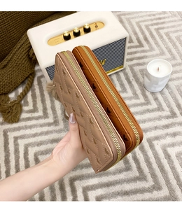 Close-up of heart embossed long wallets in light brown and tan with gold zippers