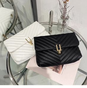 Détail de sacs matelassés noir et blanc avec fermoirs dorés sur table en verre