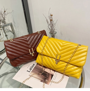 Détail de sacs matelassés jaune et marron avec coutures chevron et fermoirs dorés chic