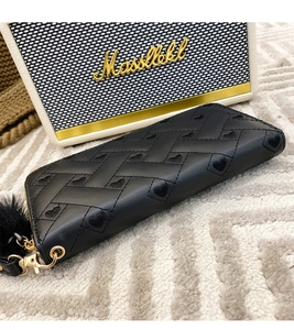 Detail of black long wallet with heart embroidery, gold zipper, and fluffy pompom charm