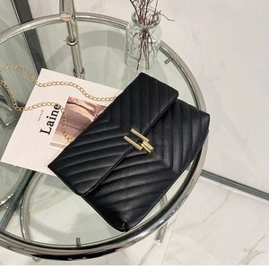 Close-up of black V-quilted faux leather bag with gold chain and metal buckle