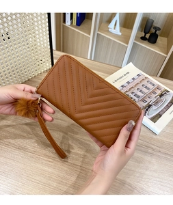 Caramel brown long wallet featuring chevron stitching and a matching fluffy pompom charm