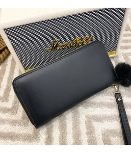 Detail of black long leather wallet featuring floral embroidery and a fur ball pendant