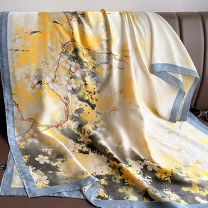 Silk satin scarf with Chinese plum blossom print draped on a leather couch
