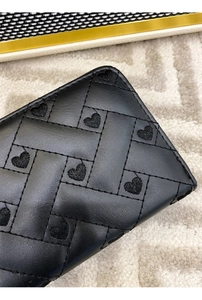 Macro shot of black leather wallet with woven quilting and embroidered heart details