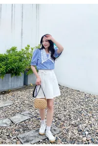 Detail of embroidered crossbody camera bag paired with a striped shirt and white skirt