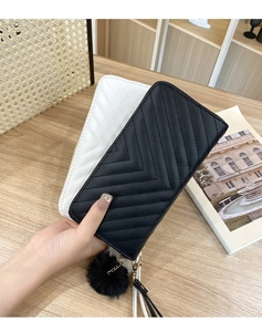 Close-up of chevron quilted long wallets with gold hardware and plush pompom charm