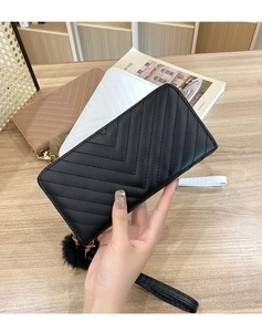 Close-up of V-quilted women's long clutch wallets with wristlets and pompom charms