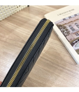 Detailed close-up of a black quilted wallet with high-quality gold metal zipper and stitching