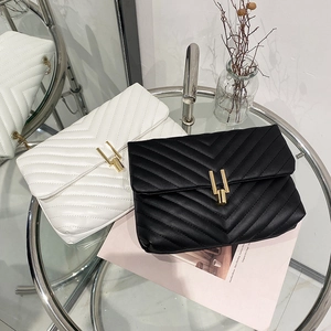 Sac bandoulière matelassé en V avec fermoir doré vertical en cuir noir et blanc