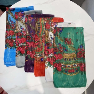 Detail of floral polyester scarves with gold silk stripes in multiple colors on marble
