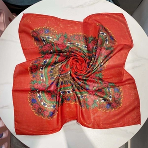 Macro detail of red floral silk scarf with golden metallic stripes in a swirl fold