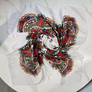 Detail of ethnic floral scarf with red roses and gold thread on white marble background
