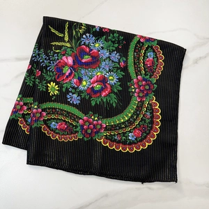 Ethnic style black floral scarf with golden stripes and colorful patterns on white marble