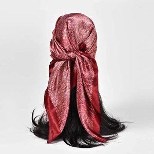 Détail d'un foulard en satin bordeaux à motif blanc noué sur les cheveux soyeux