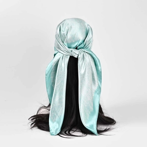 Carré de satin vert menthe utilisé comme foulard élégant sur de longs cheveux noirs