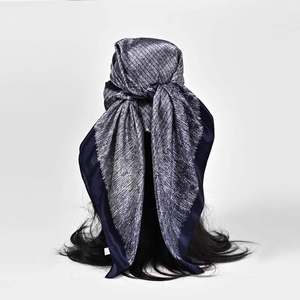 Carré de soie en satin bleu foncé à pois blancs porté en foulard sur un mannequin