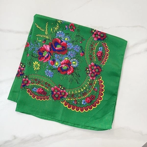 Close-up of green cotton scarf with gold silk stripes and colorful floral embroidery