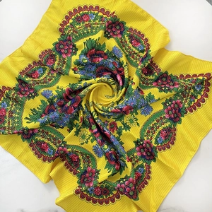 Detail of yellow ethnic square scarf featuring intricate red rose patterns and gold silk thread