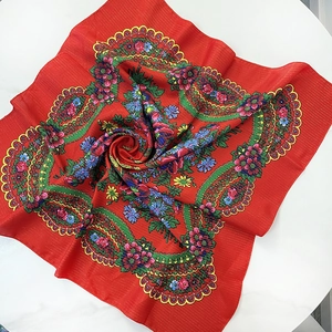 Detail of red vintage ethnic square scarf with paisley floral patterns and woven texture