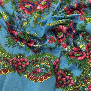 Detailed close-up of blue ethnic scarf fabric with gold metallic thread and poppy floral print
