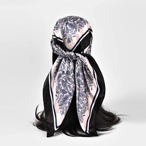 Detail view of pink paisley satin scarf tied on hair with classic black striped borders
