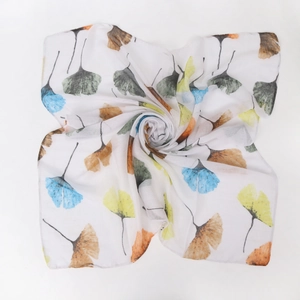 Detailed view of colorful ginkgo leaf print on white linen-cotton scarf fabric texture