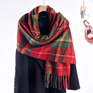 Classic green and red plaid scarf with fringe tassels on a black wool coat