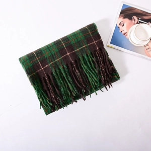 Close-up of green and brown plaid scarf with fringe tassels on a white minimalist background