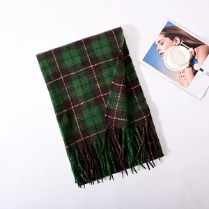 Detail of green and brown plaid scarf with fringe tassels and soft cashmere-like texture