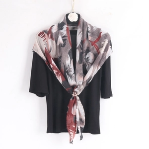 Detail of a lightweight voile scarf featuring abstract feather prints and floral accents