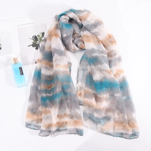 Détail d'une écharpe légère en tie-dye aux rayures dégradées bleues, grises et crème