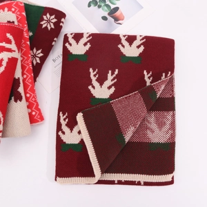 Close-up of festive red and green knitted scarf with reindeer and snowflake patterns
