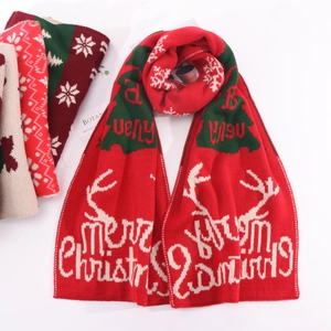 Detail of red Christmas knit scarf with white reindeer and snowflake jacquard patterns