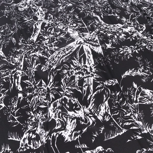 Gros plan du foulard en soie noir et blanc avec motifs de grues, fleurs et texture sergée