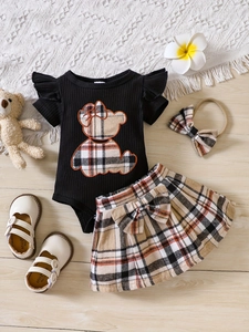 Ensemble bébé fille avec body ours à carreaux, jupe, bandeau et chaussures sur tapis